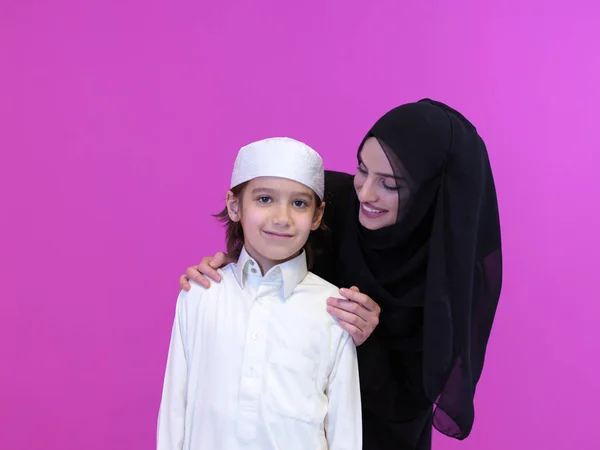 幸福的阿拉伯家庭的肖像穆斯林母亲和儿子穿着传统衣服 背景是粉色的 图库图片