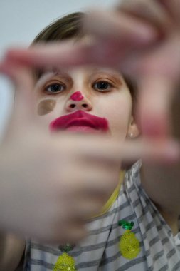 Annesinin makyajıyla oynayan tatlı bir anaokulu kızı. Moda deneyi küçük bir çocuk makyaj ruju sürüyor ve yüzüne gölge sürüyor, Corona virüsü karantinasında kalıyor..