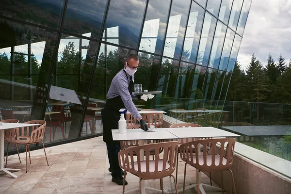 Servitören Rengör Bordet Med Desinfektionsmedel Spray Restaurang Med Skyddande Medicinsk — Stockfoto