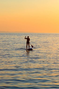 Gün batımında açık denizde kürek çekerek ayağa kalk.