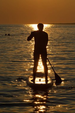 Gün batımında açık denizde kürek çekerek ayağa kalk.