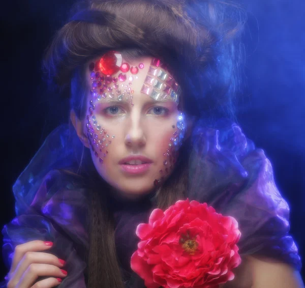 Jeune femme avec visage artistique tenant grande fleur rouge — Photo