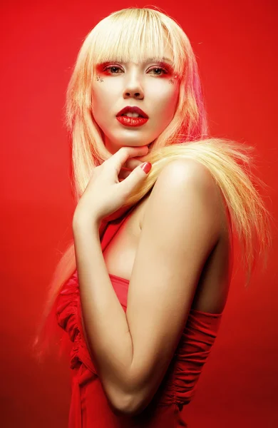 Perfecte blond model in rode jurk op rode achtergrond. — Stockfoto