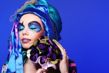 Yaratıcı makyajlı bir kadın bir buket mücevher tutuyor.