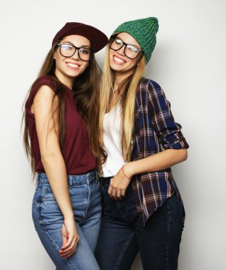 İki genç kız arkadaş birlikte durup eğleniyorlar.