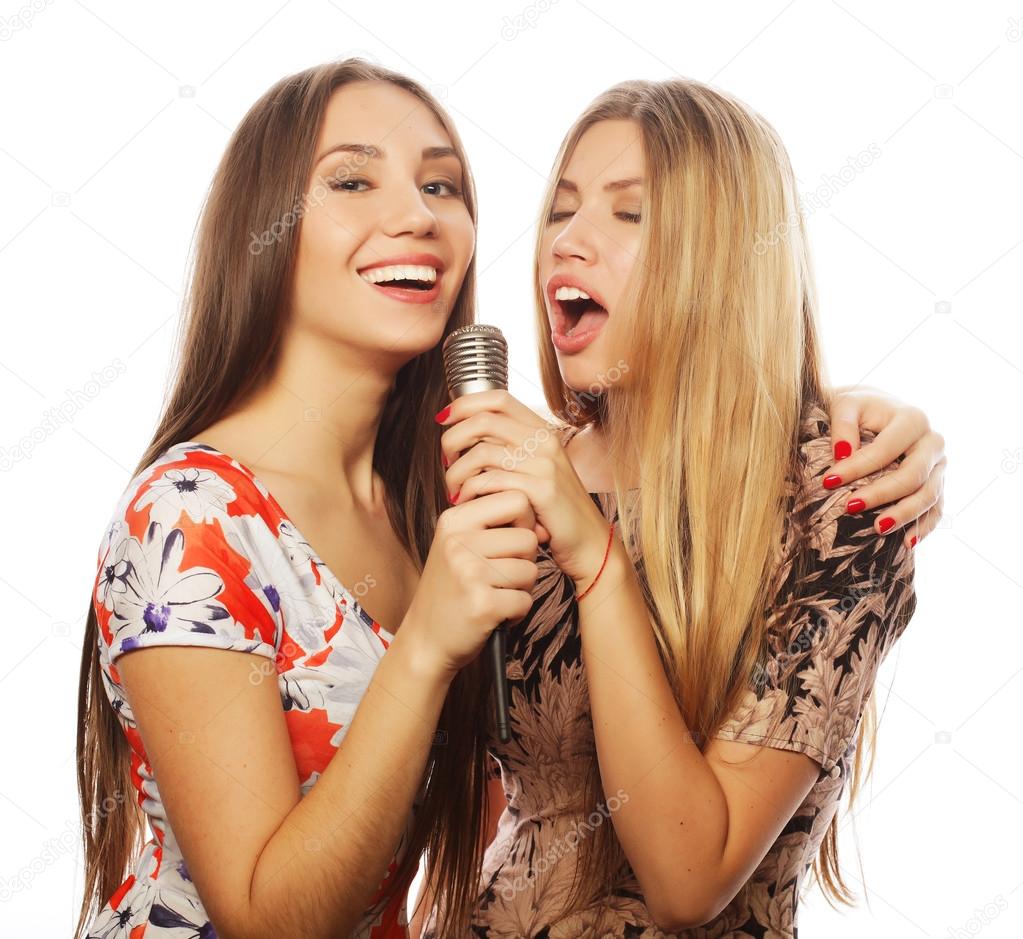 two beauty girls with a microphone singing and having fun