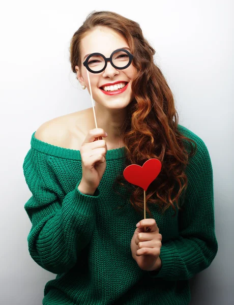 Jovencita juguetona sosteniendo unas gafas de fiesta . — Foto de Stock