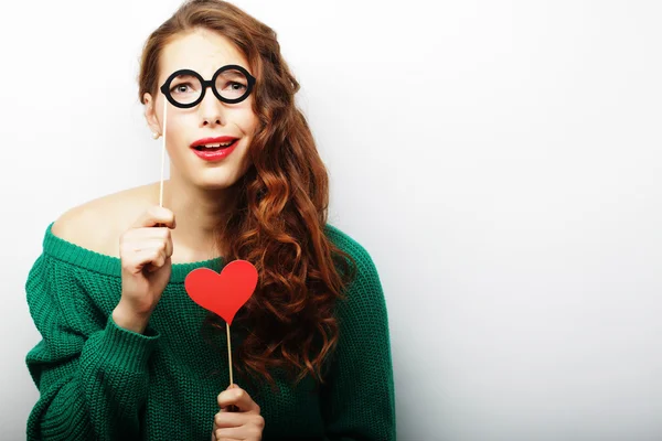 Jovencita juguetona sosteniendo unas gafas de fiesta . — Foto de Stock