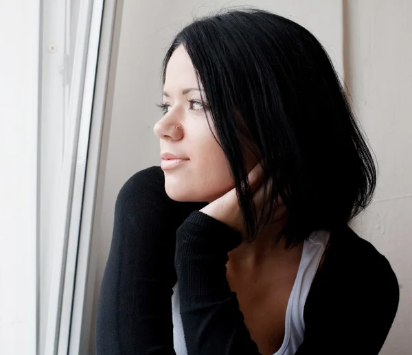 Mujer mirando a través de una ventana . — Foto de Stock