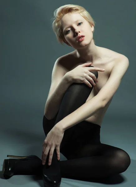 Mujer seductora sentada en pose de moda usando pantimedias negras —  Fotos de Stock