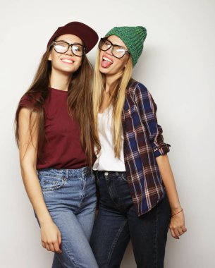 İki genç kız arkadaş birlikte durup eğleniyorlar.