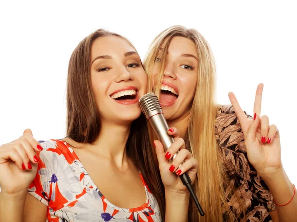 Dos chicas de belleza con un micrófono cantando y divirtiéndose — Foto de Stock