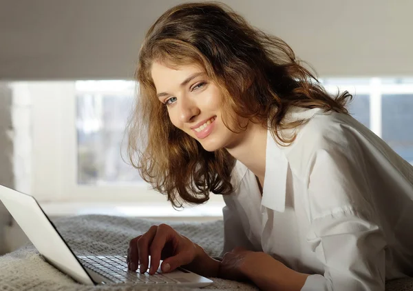 Jovem mulher em casa na cama usando laptop . — Fotografia de Stock