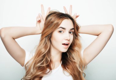 Beyaz tişörtlü, beyaz arka planda poz veren güzel bir kadın.