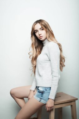 Genç, güzel kıvırcık kadın beyaz arka planda poz veriyor.