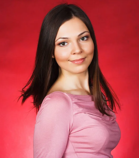 Genç kadın uzun saçlı stüdyoda kırmızı arka plan üzerinde poz — Stok fotoğraf