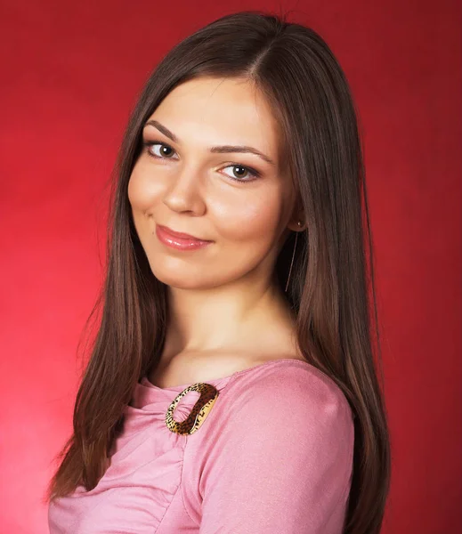 Молодая женщина с длинными волосами позирует в студии на красном фоне — стоковое фото