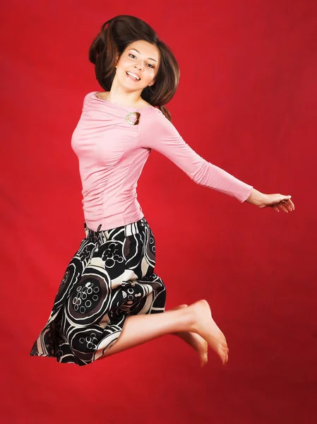 Mujer joven con el pelo largo posando en el estudio sobre fondo rojo — Foto de Stock