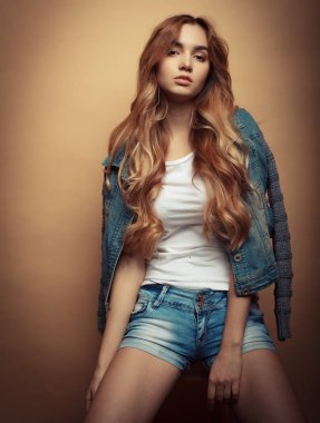 Genç güzel kıvırcık kadın sarı arka plan üzerinde poz