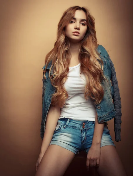 Genç güzel kıvırcık kadın sarı arka plan üzerinde poz