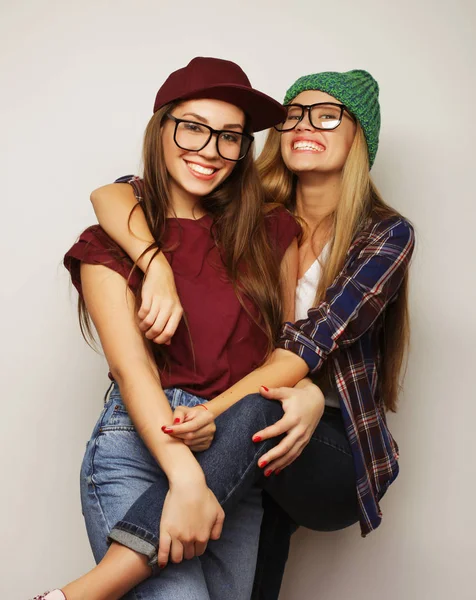 İki genç kız arkadaş birlikte durup eğleniyorlar.