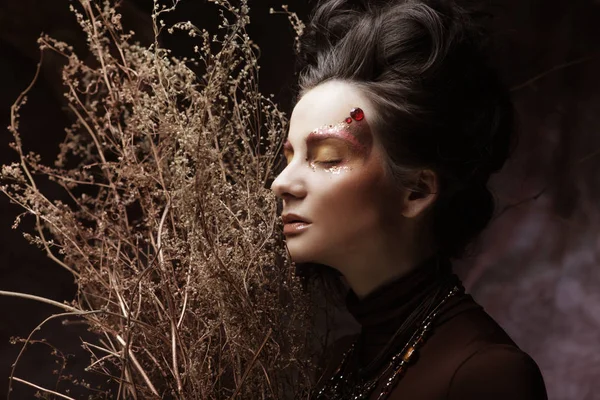 Ung kvinna med ljusa make up med torra grenar — Stockfoto