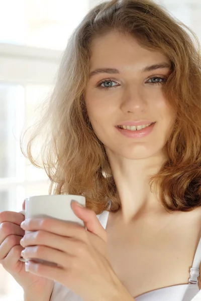Красива жінка в білій білизні п'є каву в мо — стокове фото