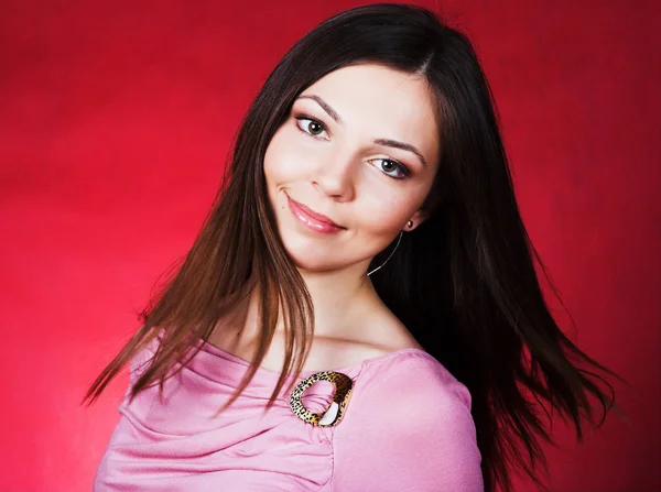 Mujer joven con el pelo largo posando en el estudio sobre fondo rojo — Foto de Stock