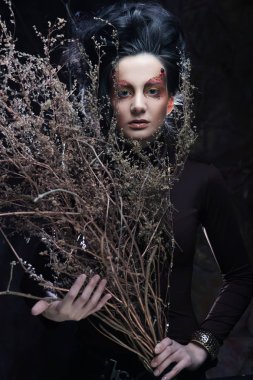 Kuru dallarla parlak makyajlı genç bir kadın