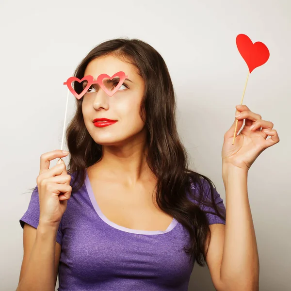 Jovencita juguetona sosteniendo unas gafas de fiesta . — Foto de Stock