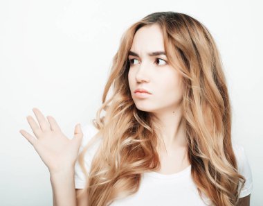 Beyaz tişörtlü, beyaz arka planda poz veren güzel bir kadın.