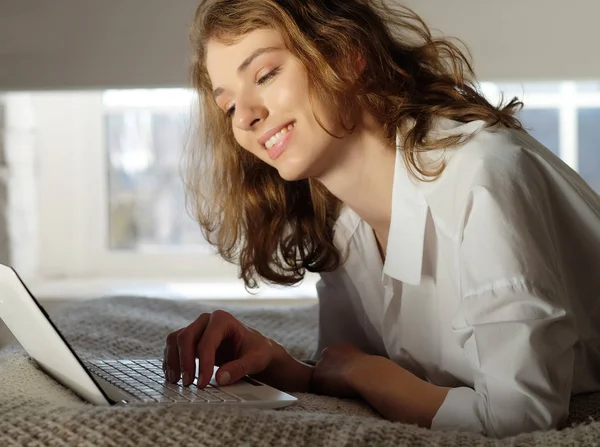 Mujer joven en casa en la cama usando el ordenador portátil . —  Fotos de Stock