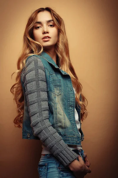 Genç güzel kıvırcık kadın sarı arka plan üzerinde poz