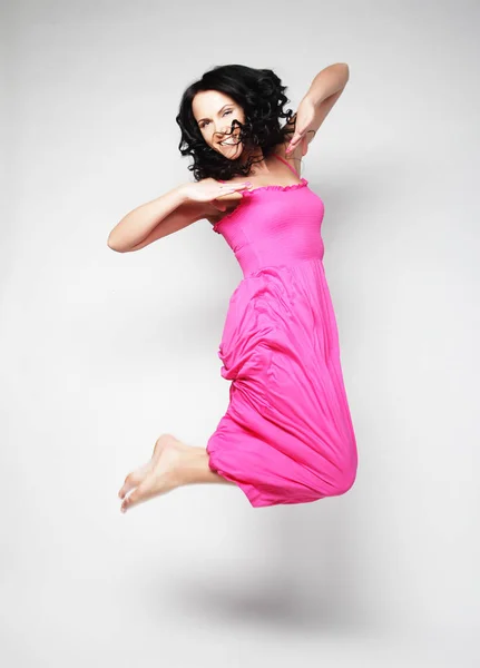 Mujer saltando. Feliz chica emocional con vestido rosa . — Foto de Stock