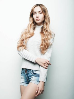 Beyaz tişörtlü, beyaz arka planda poz veren güzel bir kadın.