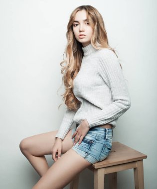 Genç, güzel kıvırcık kadın beyaz arka planda poz veriyor.