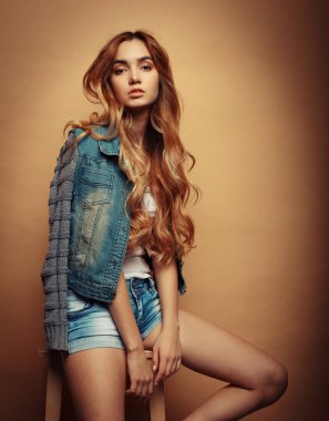 Genç güzel kıvırcık kadın sarı arka plan üzerinde poz