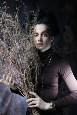 Kuru dallarla parlak makyajlı genç bir kadın