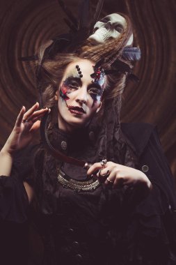 Genç cadı hloding orak. Parlak makyaj, kafatası, sigara... Cadılar Bayramı teması.