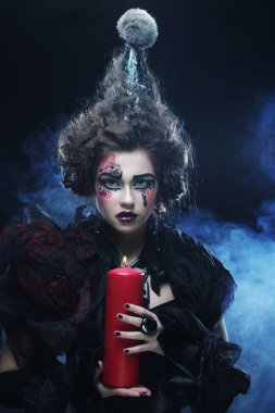 Elinde mum tutan karnaval kostümü giyen genç bir kadın..