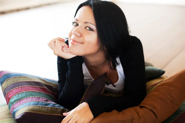 Kobieta siedzi i uśmiechający się w pomieszczeniu — Zdjęcie stockowe