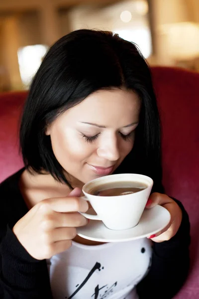 Jovem mulher sentada em um café bebendo café — Fotografia de Stock