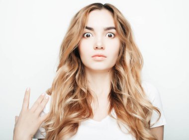 Beyaz tişörtlü, beyaz arka planda poz veren güzel bir kadın.