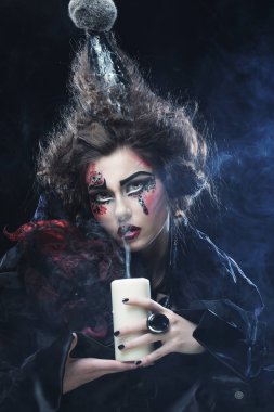 Elinde mum tutan karnaval kostümü giyen genç bir kadın..