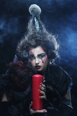 Elinde mum tutan karnaval kostümü giyen genç bir kadın..