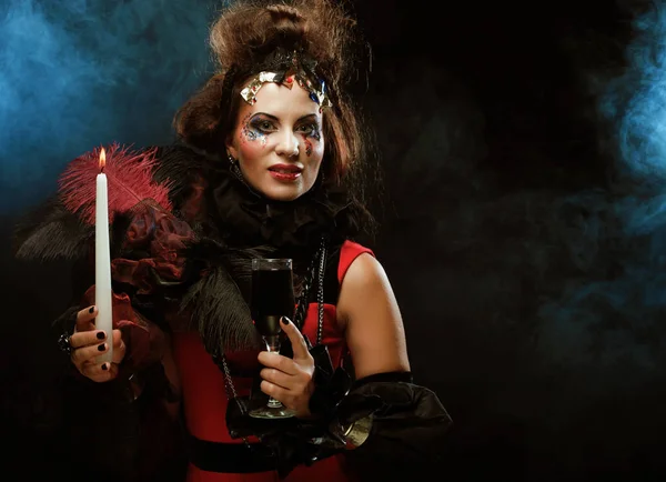 Young woman wearing carnival costume holding a candle. — Stock Photo, Image