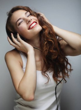 Kulaklıklı genç bir kadın müzik dinliyor.