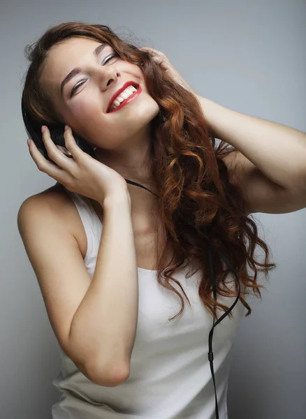 Ung kvinna med hörlurar lyssnar musik — Stockfoto