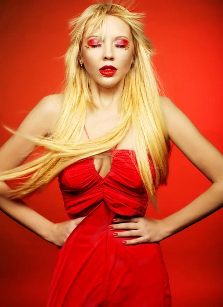 Doskonały model blond w czerwonej sukience na czerwonym tle. — Zdjęcie stockowe