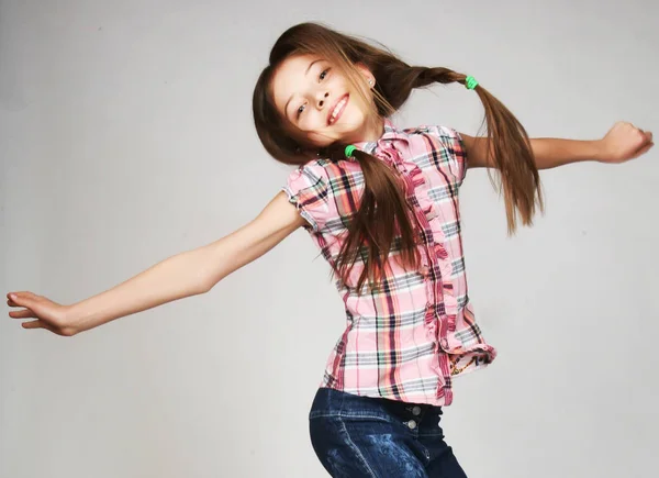 Little girl jumps on a gray  background — Stock Photo, Image